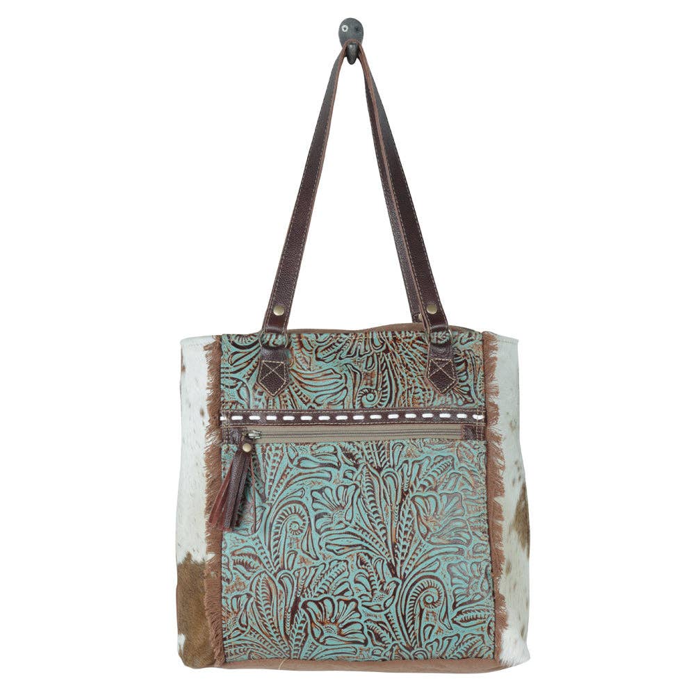 Amethyst Canvas & Hairon Pouch featuring a decorative pattern, zip closure, and tassel detail in shades of blue and brown.