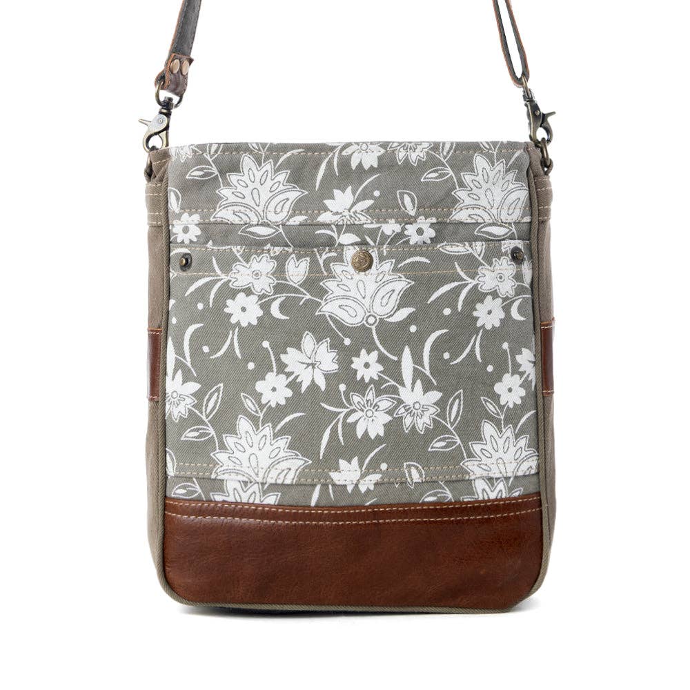 Blossom print shoulder bag featuring floral patterns, brown leather bottom, and shoulder strap with a snap button closure.