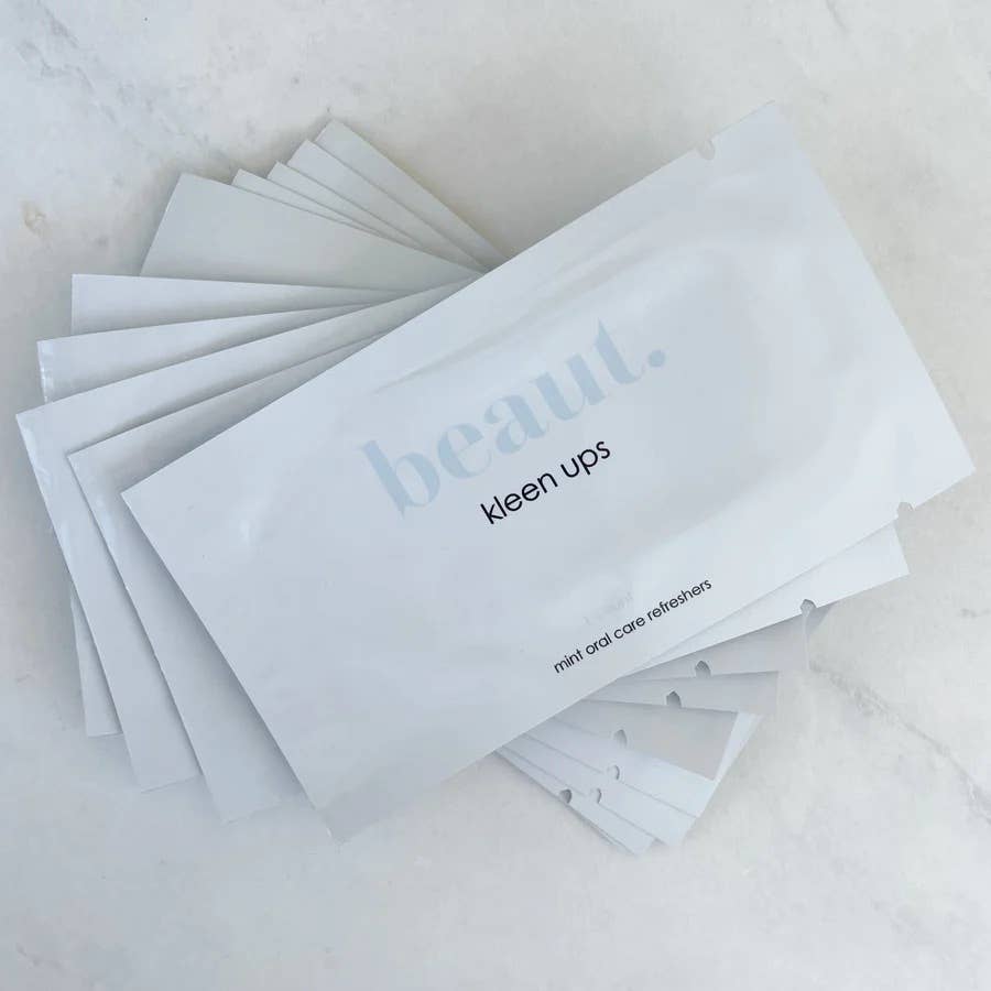 A stack of individually sealed packets labeled 'Kleen Ups' containing mint oral care refreshers for freshening breath on the go.