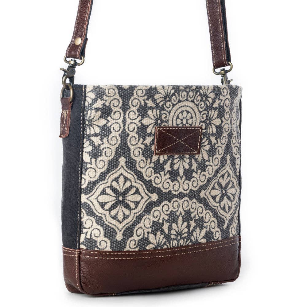 Stylish shoulder bag featuring a patterned fabric front, leather bottom, and adjustable strap for everyday use.