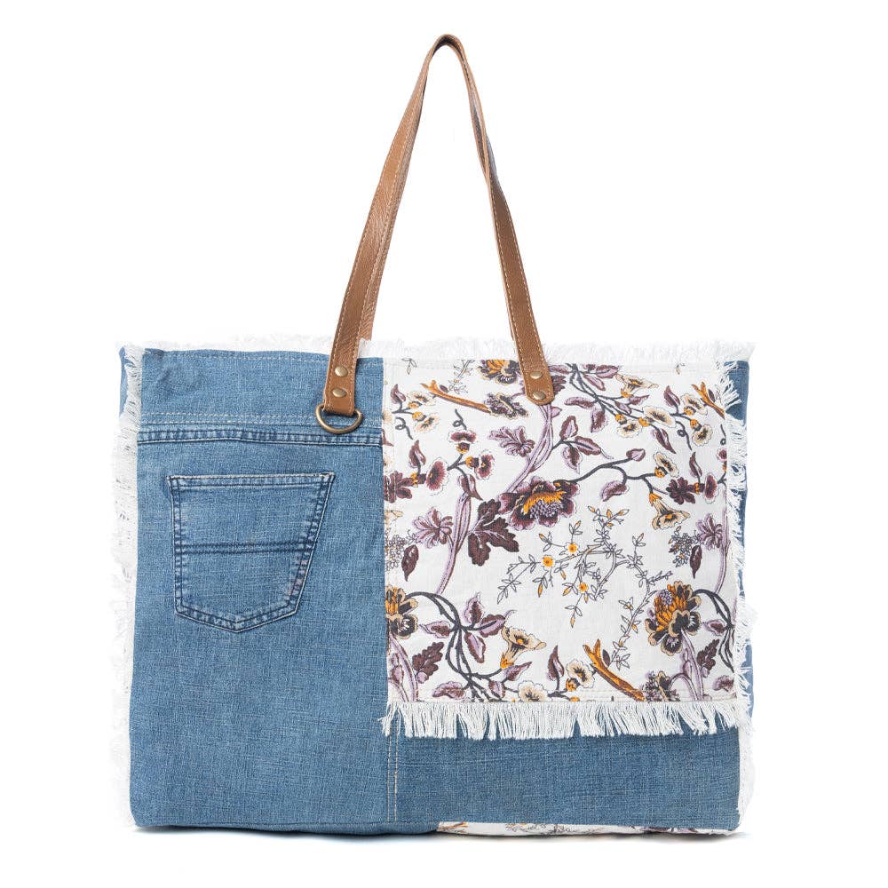 Floral cotton weekender bag featuring fringe detailing and a durable leather shoulder strap, perfect for your next adventure.