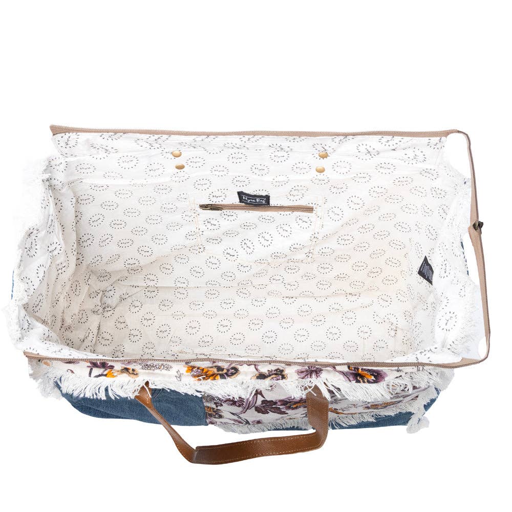 Floral cotton weekender bag featuring fringe detailing, inside zipper pockets, and a side pocket for a water bottle.