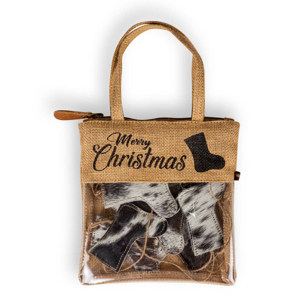 Woven burlap bag with 'Merry Christmas' design holding black hair-on hide stockings, showcasing a festive holiday look.