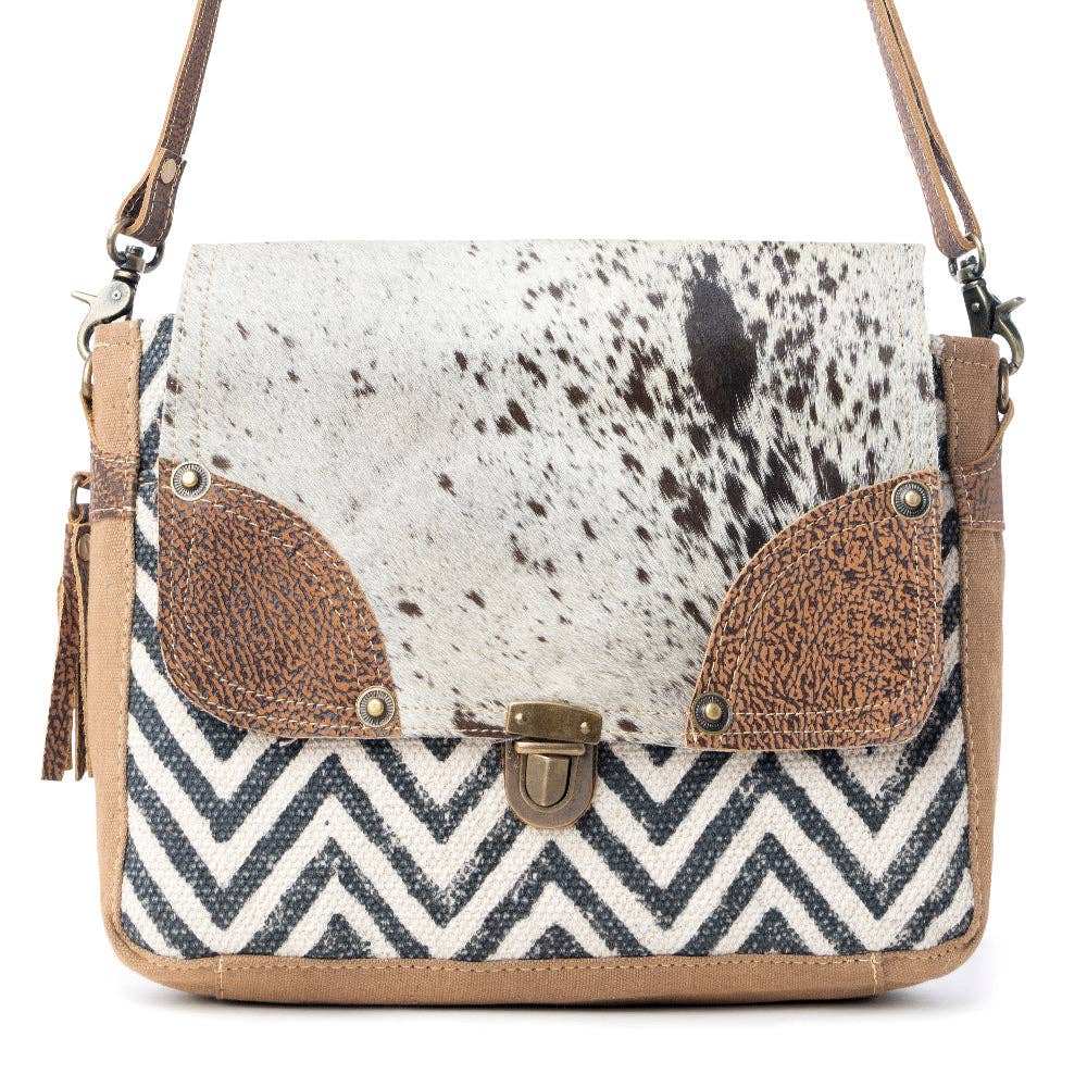 Rugged messenger bag featuring a spotted hairon flap, leather accents, and a chevron-patterned body. Perfect for everyday use.