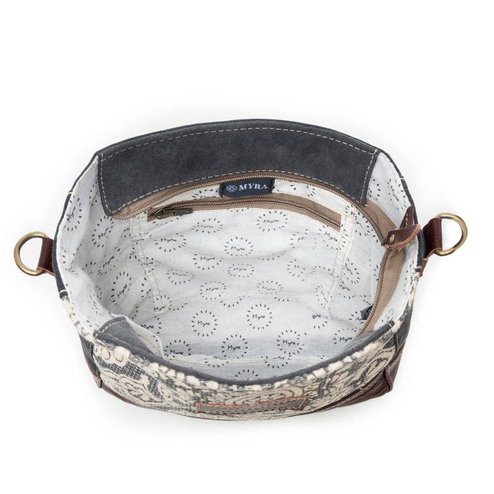 Round-shaped shoulder bag with a wide opening, featuring a patterned design and a light-colored interior lining.