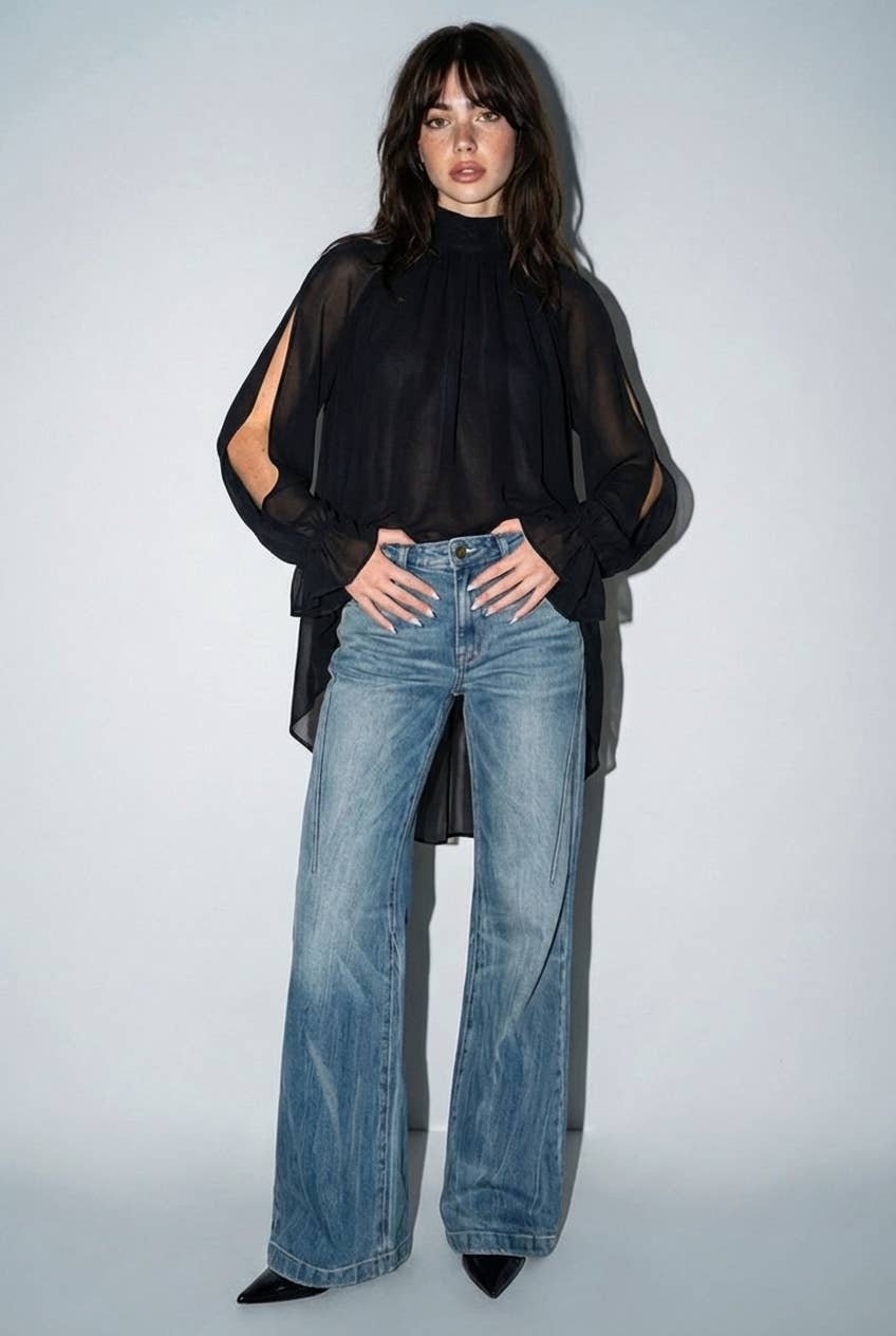 Black chiffon cold-shoulder top with a high-low hem, ruffled cuffs, and a romantic bow tie detail at the back.