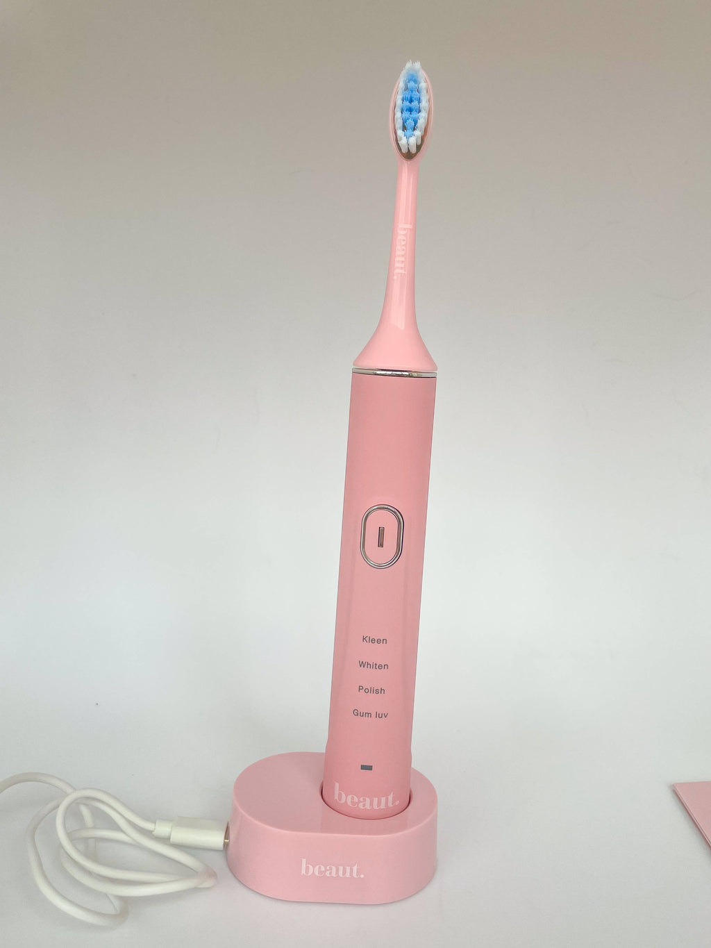 Pink Smile Kleen Sonic Vibration Toothbrush with blue and white bristle head and charging base.