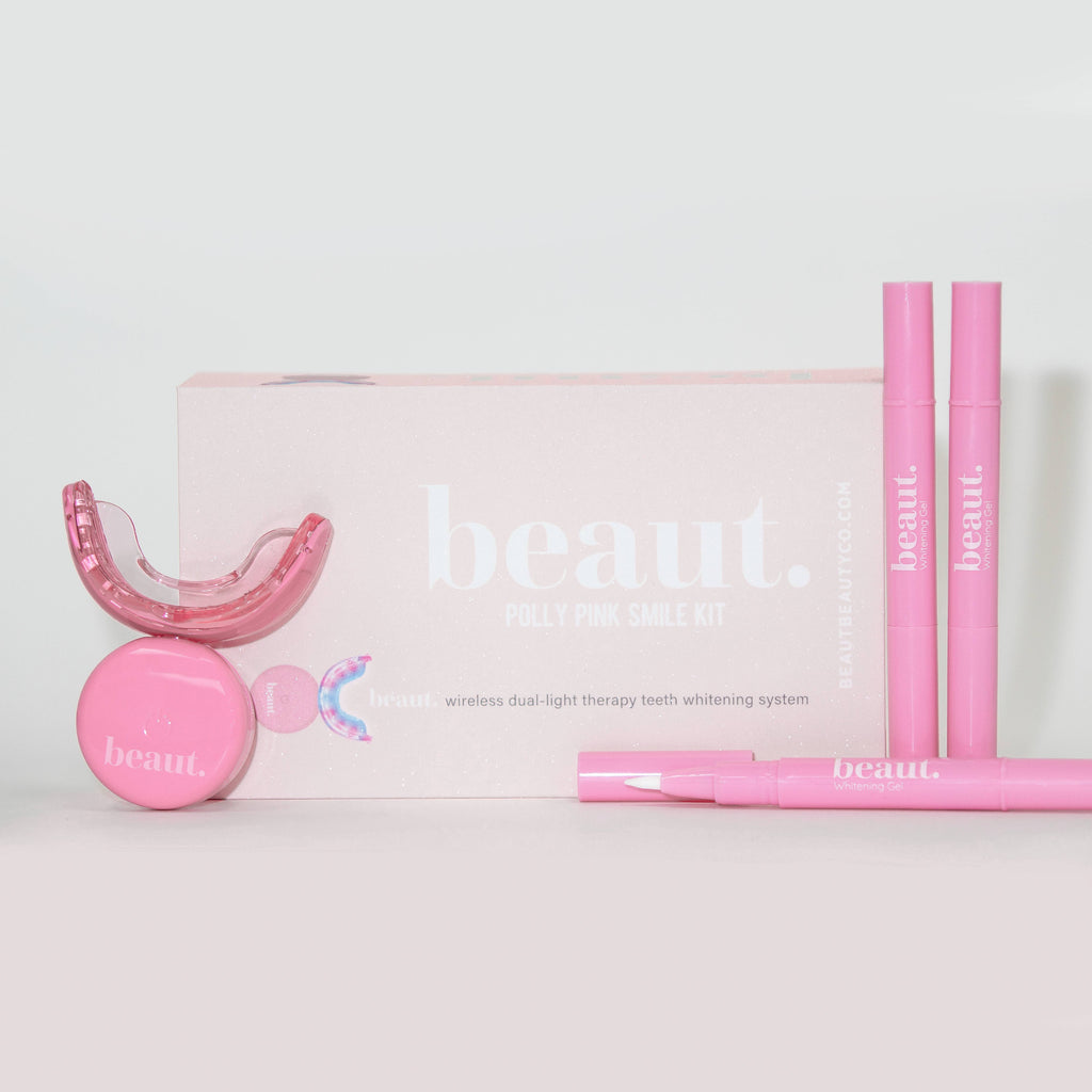 Polly Pink Kit featuring a mouthpiece, two pink smile pens, and a circular device for oral care and whitening.