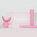 Polly Pink Kit featuring a mouthpiece, two pink smile pens, and a circular device for oral care and whitening.