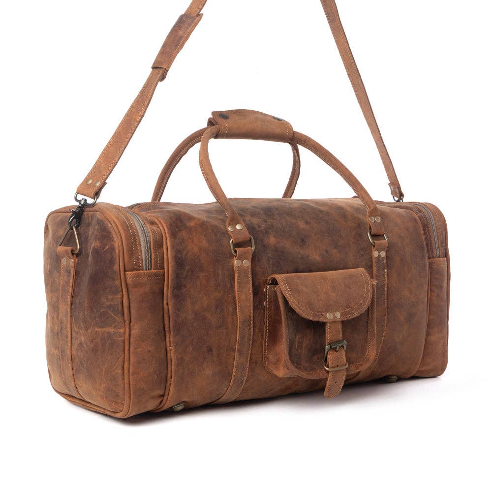 Amber brown leather traveller bag with structured shape, long shoulder strap, front flap pocket, and side zipper pocket.