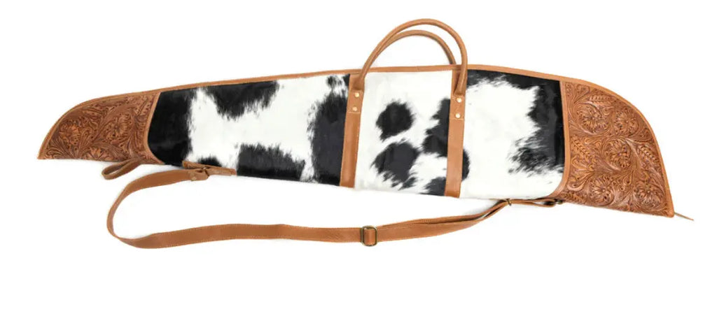 Stylish rifle case featuring black and white hair-on hide, hand-tooled leather panel, and caramel brown leather trim.