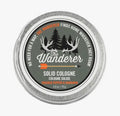 Round tin of The Wanderer Solid Cologne featuring a design with trees and antlers, scented with cracked pepper and mandarin.