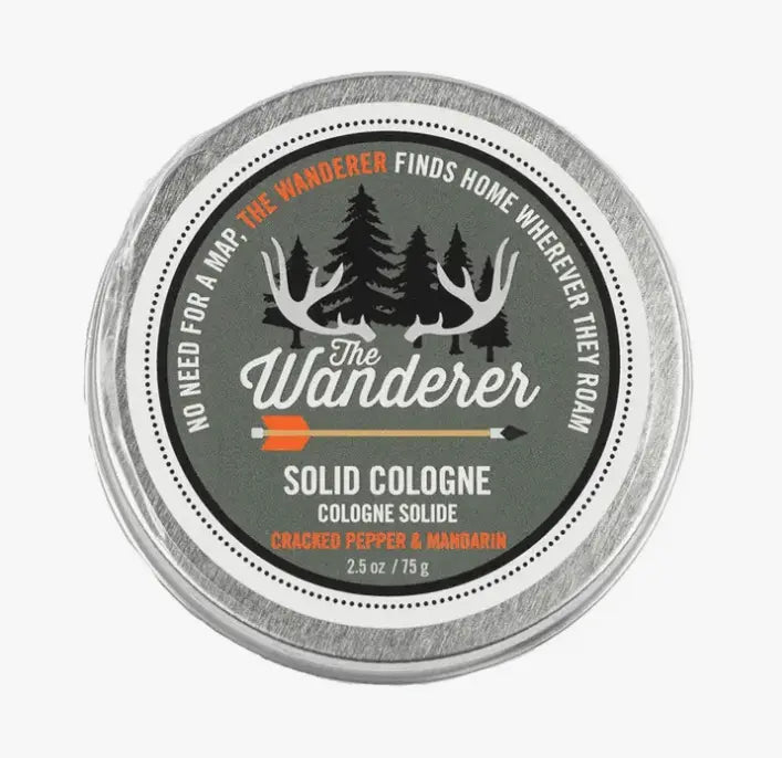 Round tin of The Wanderer Solid Cologne featuring a design with trees and antlers, scented with cracked pepper and mandarin.