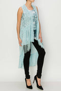 Sleeveless light blue high-low lace vest layered over black pants and high heels, showcasing its flowy design.