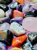 A variety of colorful, polished crystal tumble stones showcasing unique patterns and textures in different shapes and sizes.