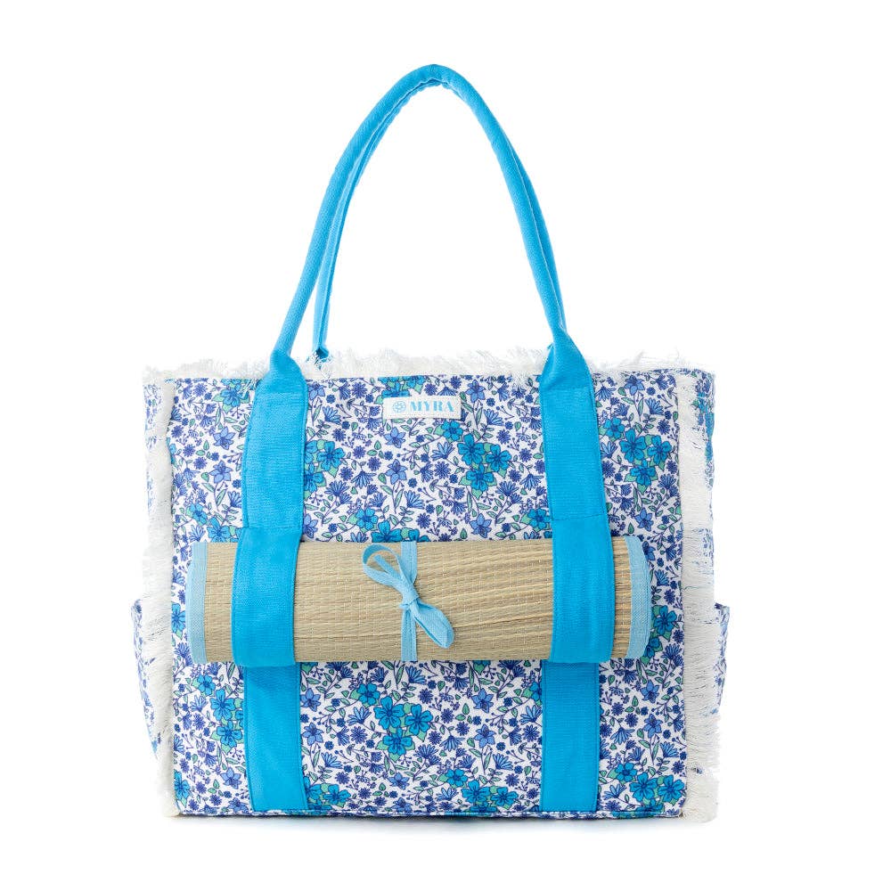 Wildflower print weekender bag with fringe detailing, desert blush carry straps, and included rolled beach mat.