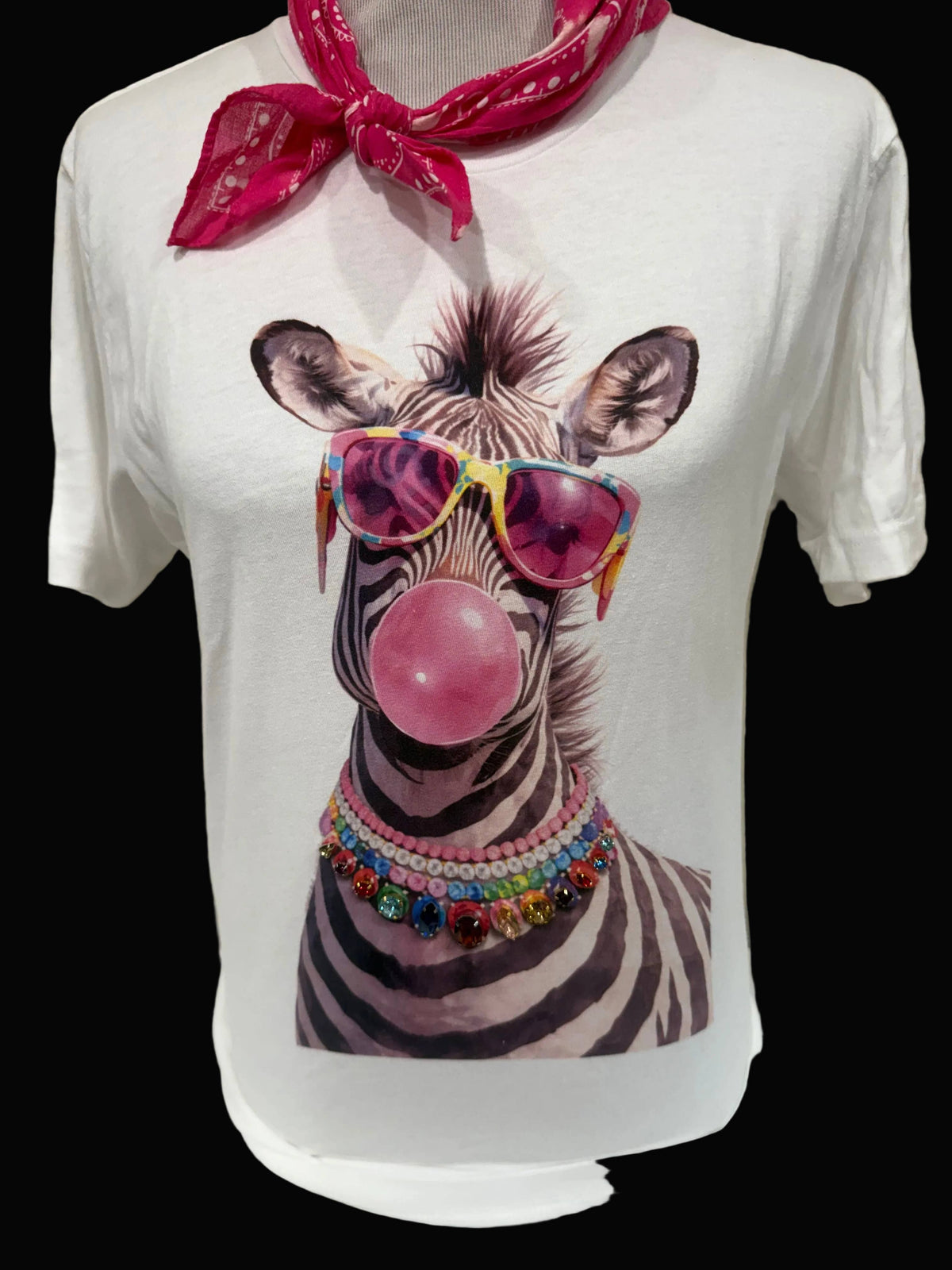 A white t-shirt featuring a zebra graphic with sunglasses and a bubblegum bubble, accented by a jeweled collar design.