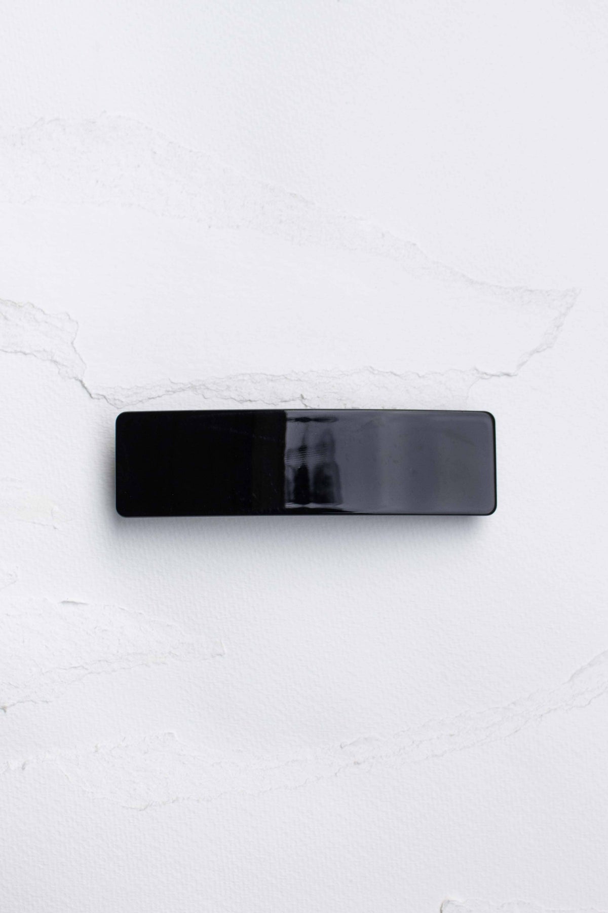 Sleek black rectangular hair barrette with a smooth, glossy finish, perfect for adding a minimalist touch to any hairstyle.