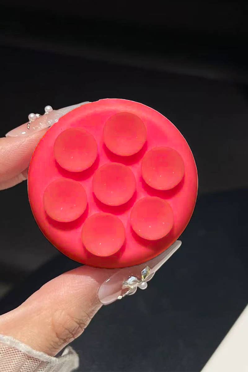 Round pink suction cup phone grip featuring a textured surface with circular indentations, perfect for secure handling.
