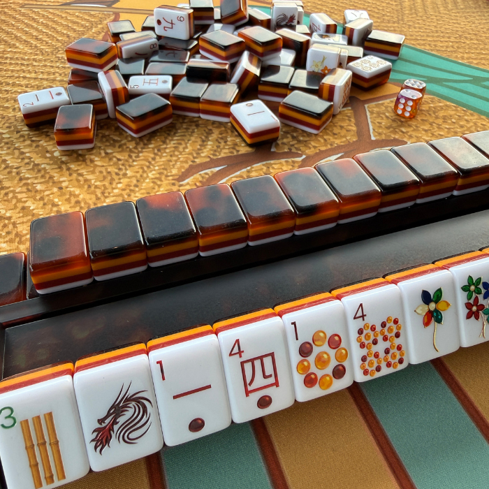 Tortoise shell Mahjong rack holding tiles in a row, showcasing the elegant design of the Mahjong Rack & Pusher Set.