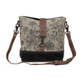 Floral canvas shoulder bag featuring a front lock closure and adjustable leather straps in a structured design.