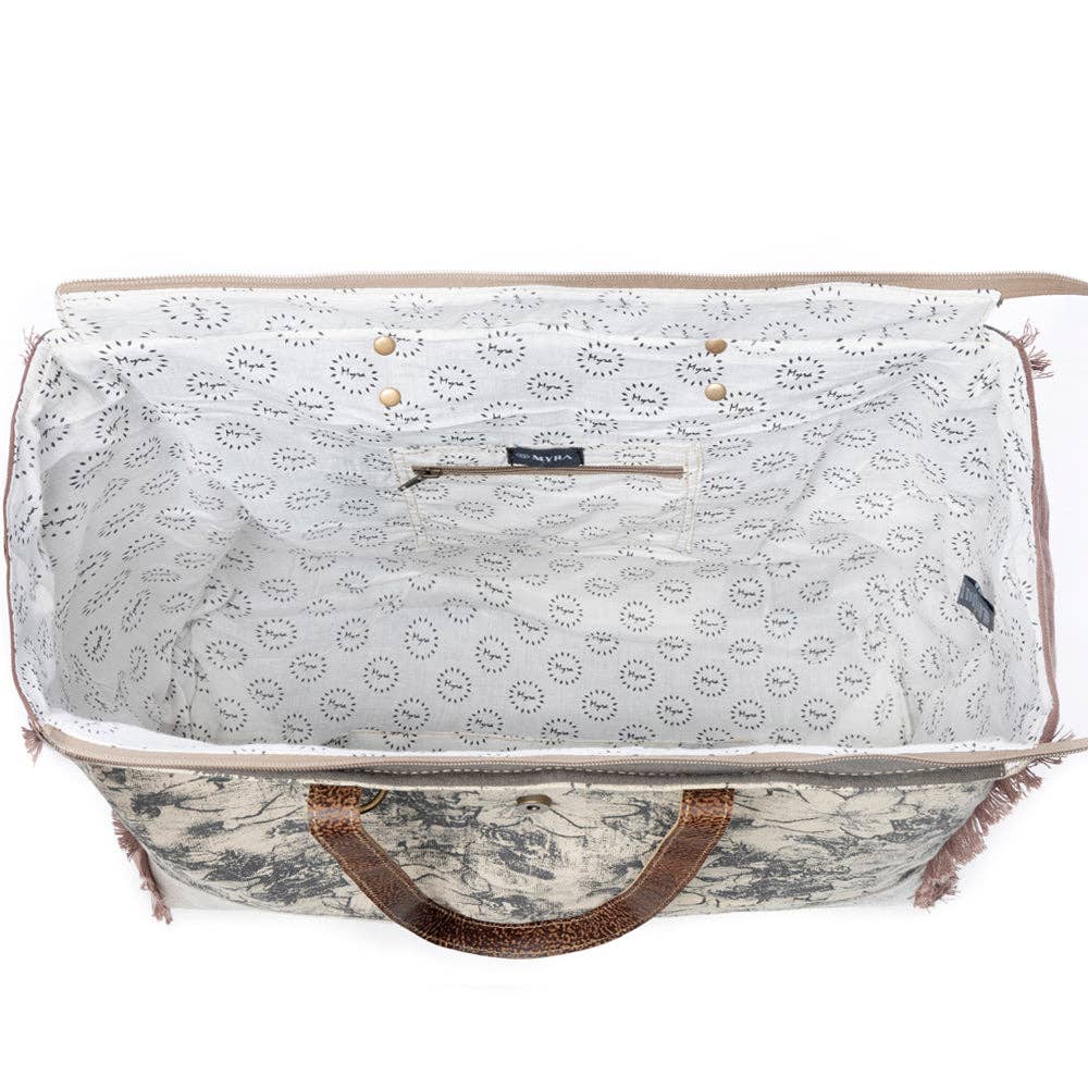 Floral design weekender bag with leather top handles and a spacious interior featuring a zipper closure.
