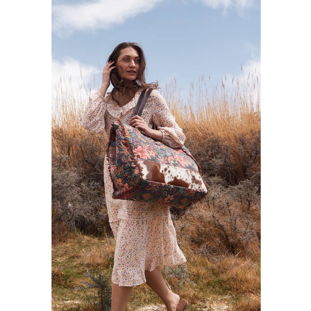 Floral weekender bag with a spacious design, perfect for adventurous getaways. Features a sturdy build and long handle for easy carrying.