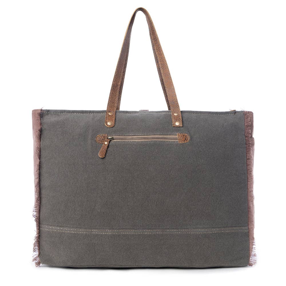 Large weekender bag featuring a zipper closure, leather top handles, and a stylish floral canvas design.