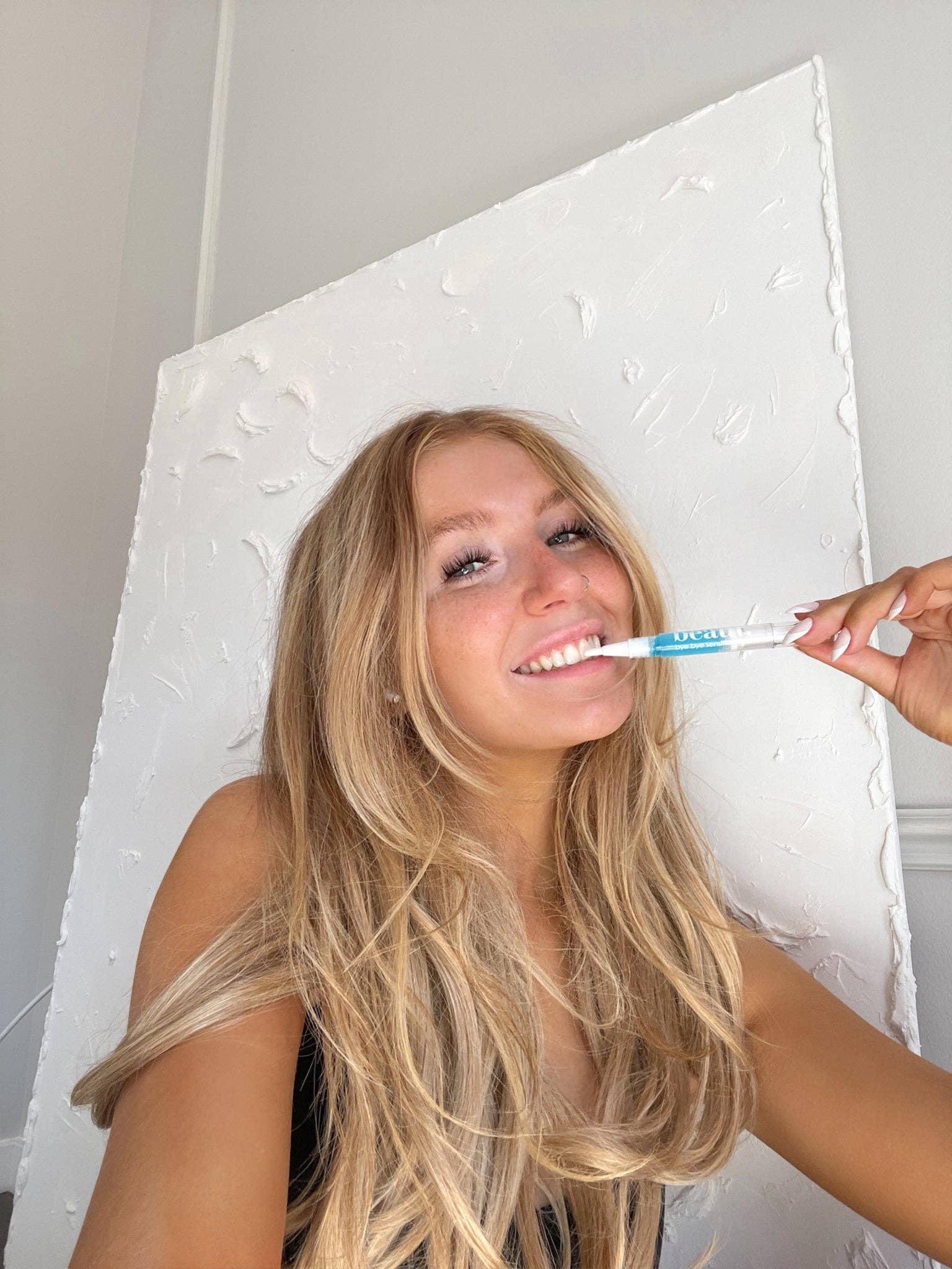 A person holding the Bye Bye Sensitivity Gel Pen, designed to help reduce teeth sensitivity with Vitamin E oil treatment.