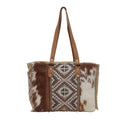 Stylish crossbody bag featuring a geometric pattern in brown and cream tones with leather straps and a structured shape.