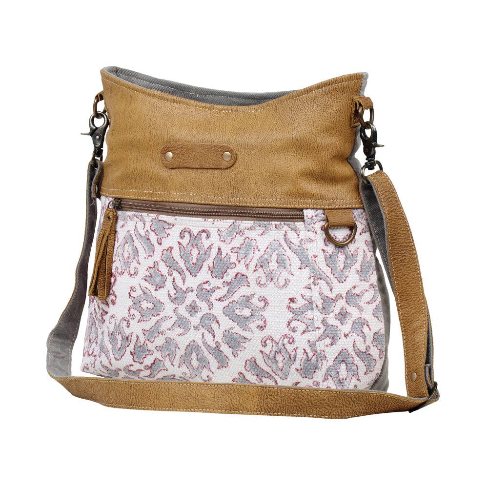 Shoulder bag featuring a patterned front, solid leather top, adjustable strap, and zipper pocket for stylish organization.
