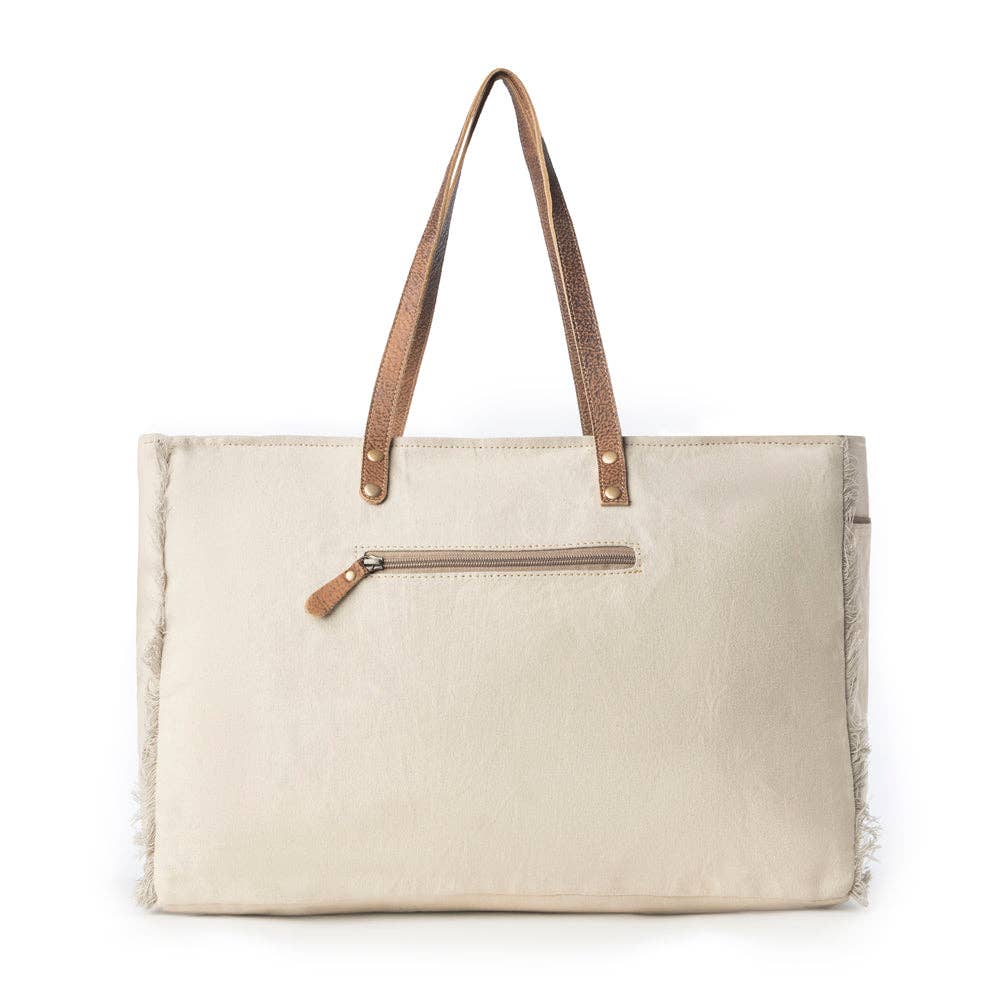 Ivory weekender bag featuring a vintage mandala print, leather handle accents, and soft fringe edges.