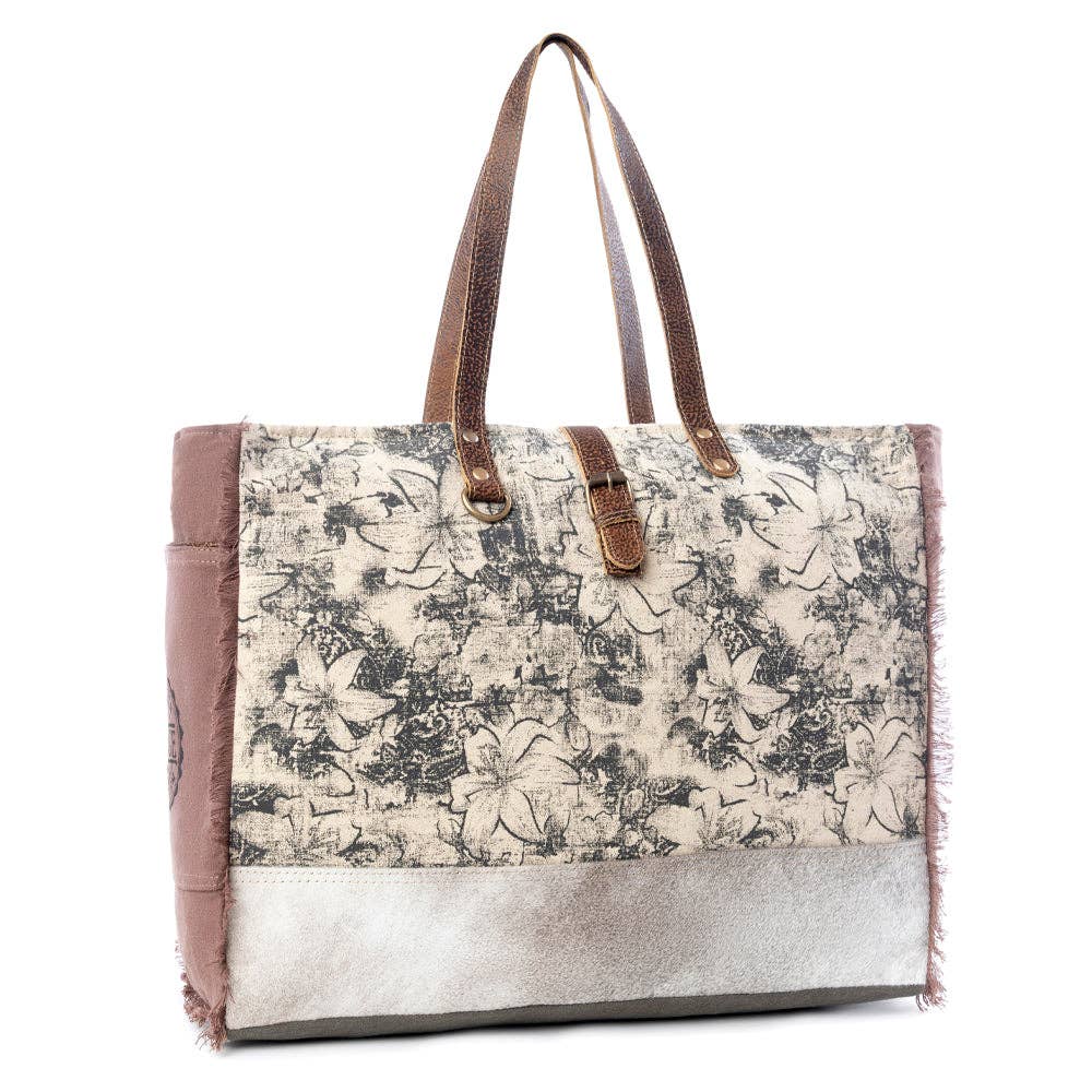 Floral canvas weekender bag with leather accents, featuring two top handles and a spacious zipper closure.