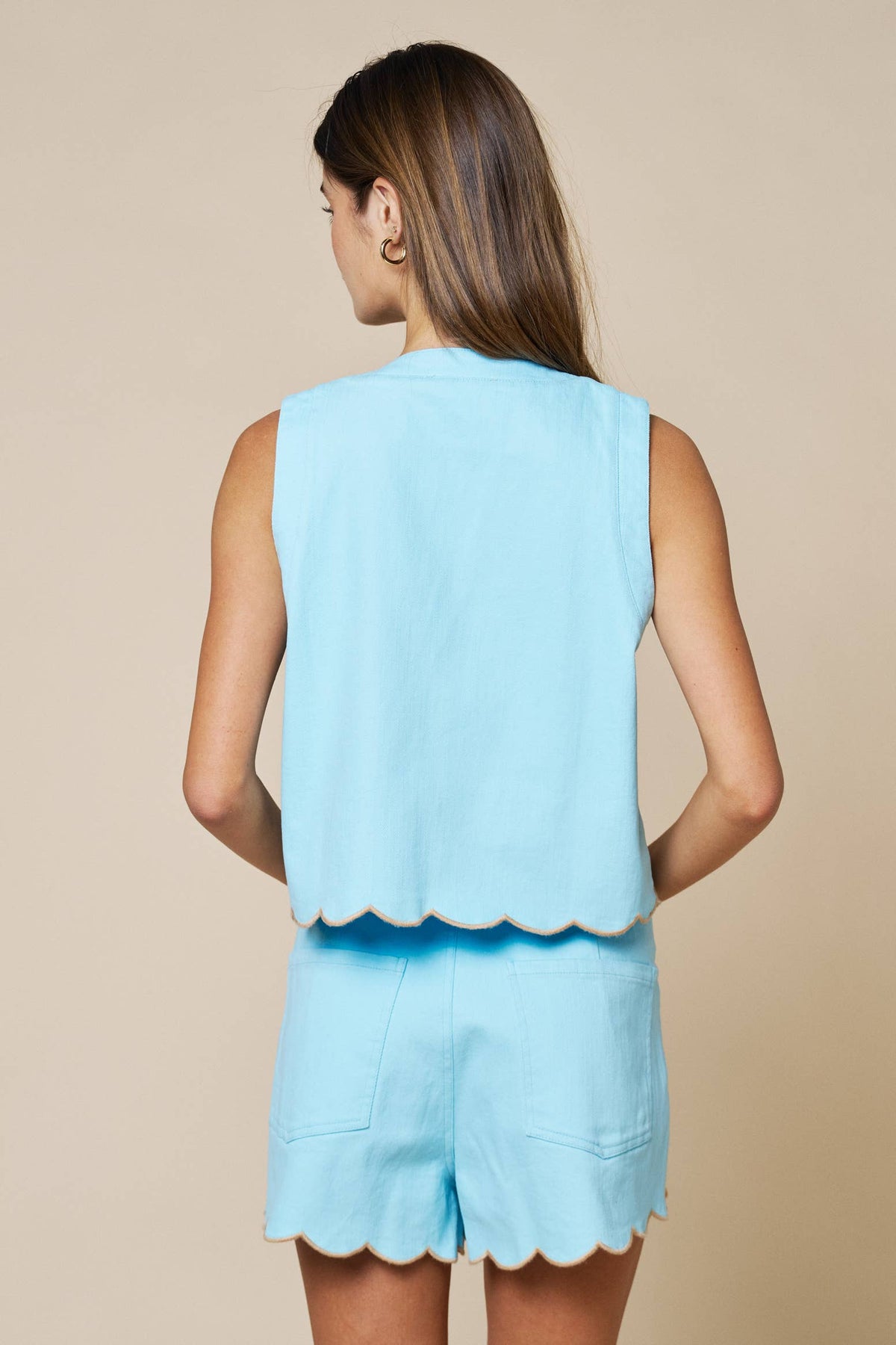 Light blue sleeveless vest with scalloped hem and floral embroidery, featuring a V-neckline and adjustable front ties.