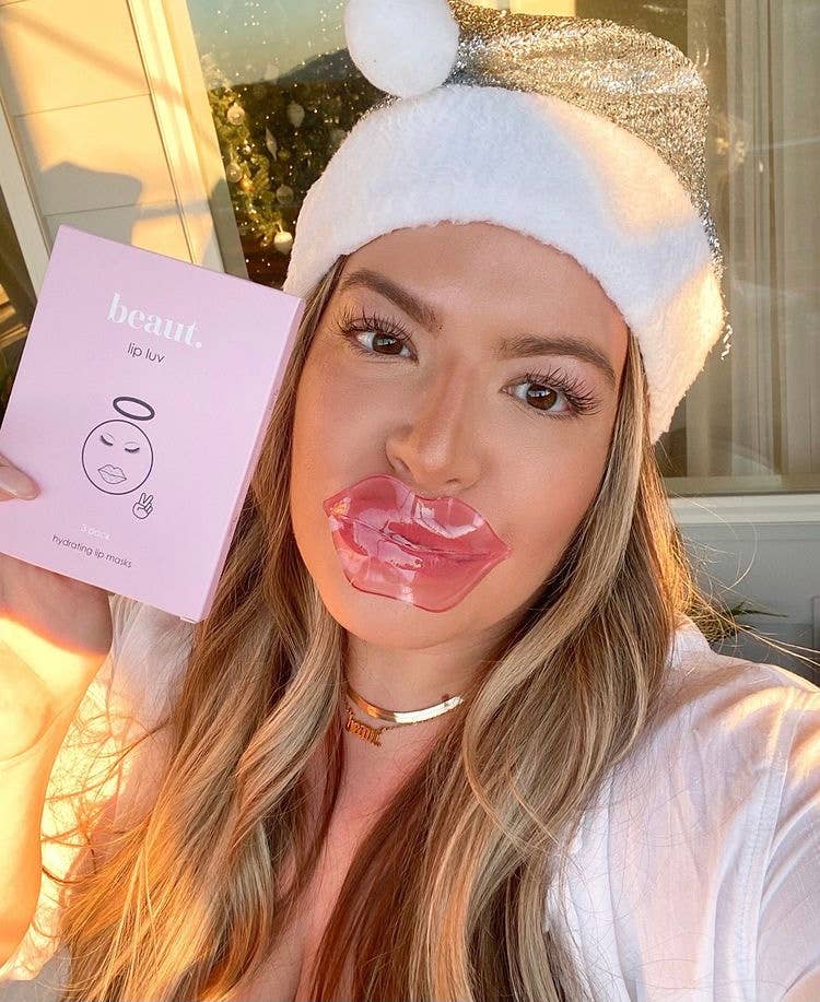 A person wearing a glossy lip mask from the Lip Luv collection, holding a pink box labeled 'Lip Luv.'