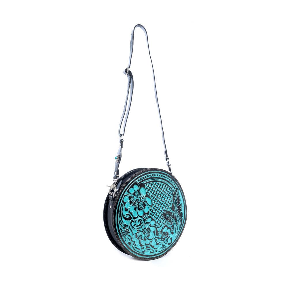 Round handbag featuring a hand-tooled turquoise and ebony design, with a detachable adjustable shoulder strap and zippered pocket.
