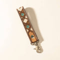 Handtooled leather keyfob featuring a natural hairon pattern in dark brown, white, and blue with decorative flowers and geometric shapes.