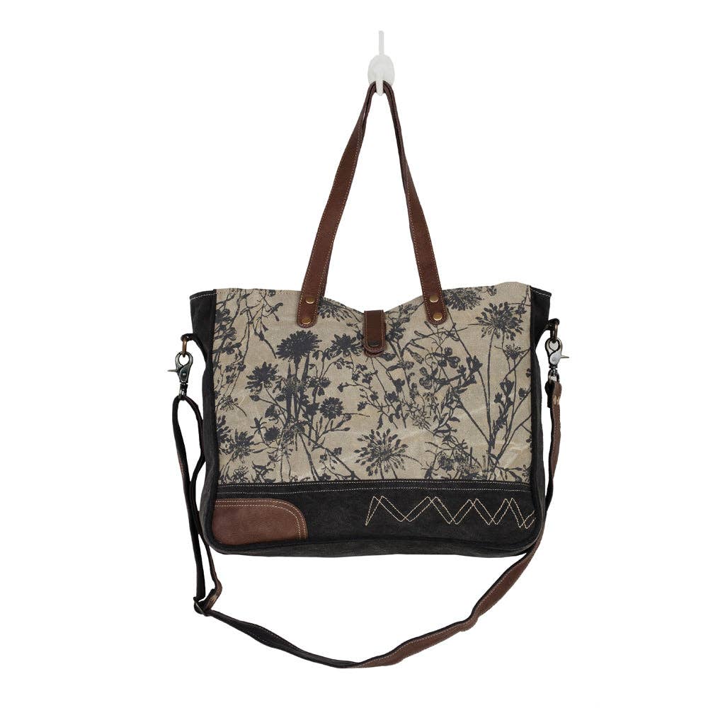 Floral-print messenger bag featuring multiple compartments, short handles, and a long adjustable shoulder strap.