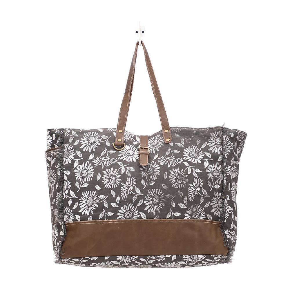 Floral weekender bag with leather trim and top handles, featuring a spacious design and zipper closure for easy access.