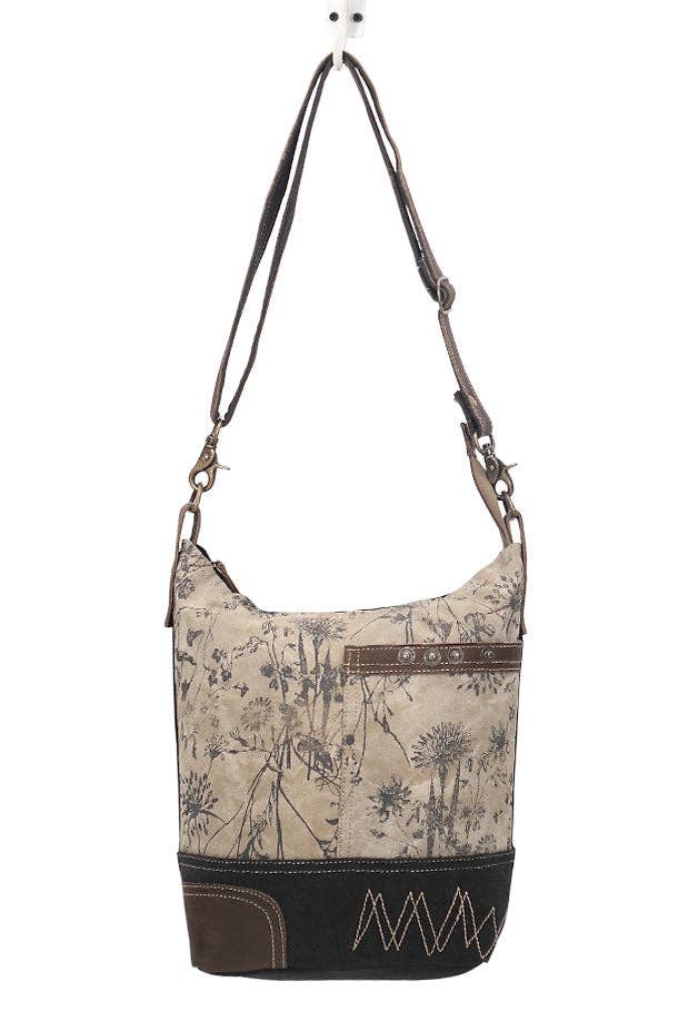 Shoulder bag featuring a floral pattern, front pocket, and decorative stitching, made from canvas and leather.