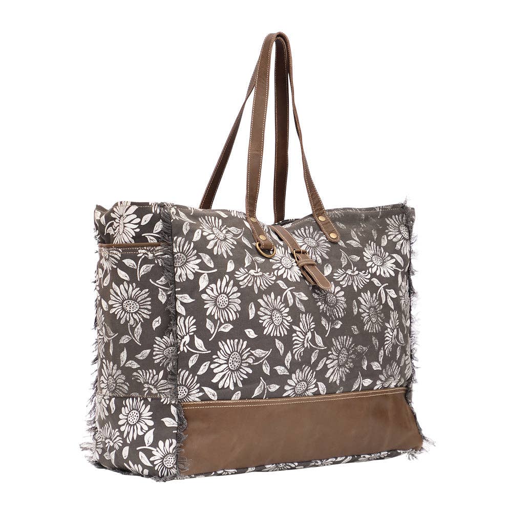 Floral weekender bag with leather trim, spacious main compartment, and zipper closure, perfect for travel and everyday use.