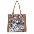 Neutral canvas and hairon bag with fringe detailing and adjustable leather strap, perfect for day or evening use.