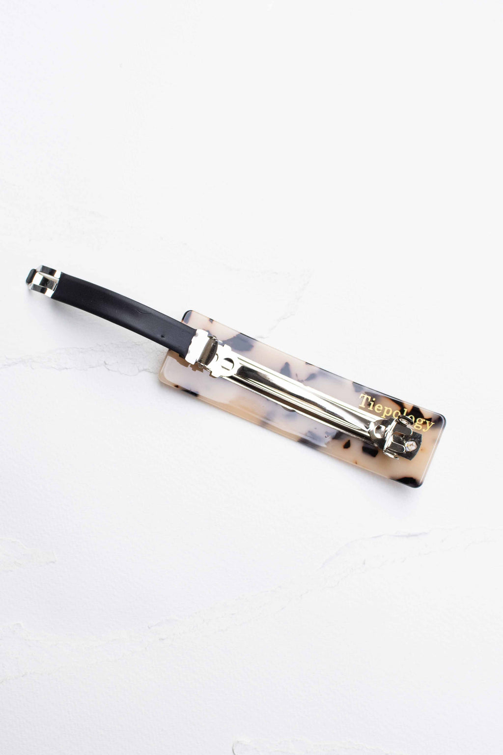 Rectangular hair barrette featuring a marbled pattern and glossy finish, secured with a durable metal clasp.