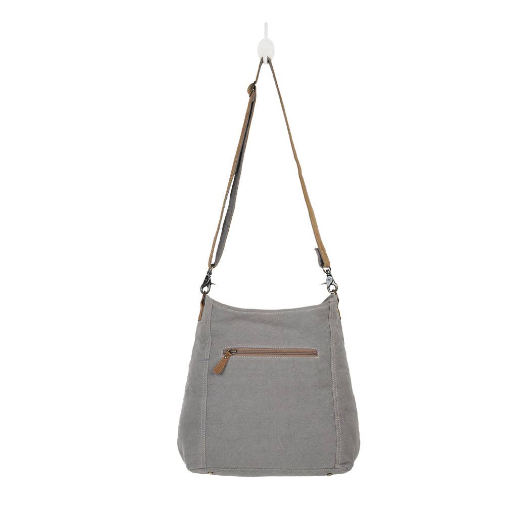 Shoulder bag in light gray with brown accents, featuring an adjustable strap and front zip pocket. Perfect for stylish outings.