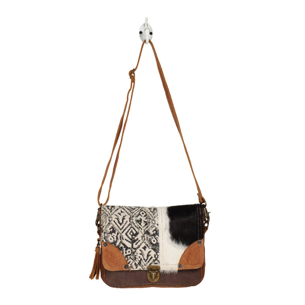 Geometric black-and-cream woven canvas messenger bag with hairon cowhide panel and tan leather accents.