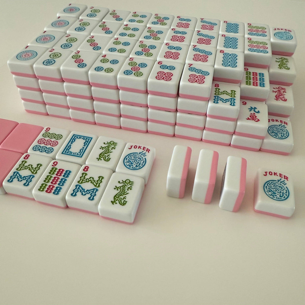 Complete set of Mahjong tiles featuring colorful designs and pink backs, showcasing 166 tiles including jokers.