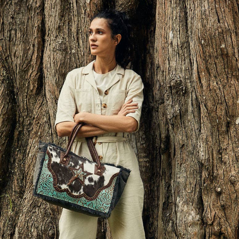 A stylish Articulate Canvas & Hairon Bag featuring a mix of textures and a bold western-style design.