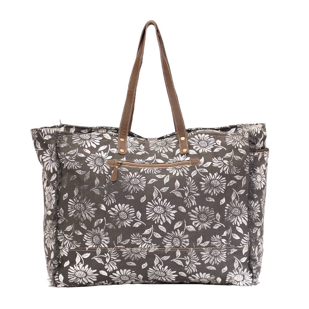 Floral weekender bag featuring leather top handles and a spacious main compartment with zipper closure.