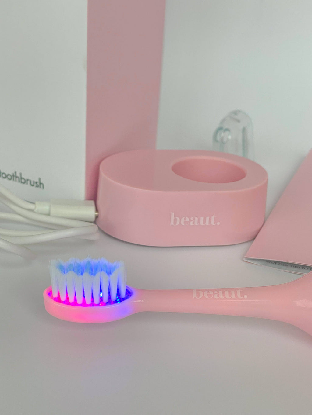 Pink Smile Kleen Sonic Vibration Toothbrush with blue and red light feature, accompanied by a matching holder.