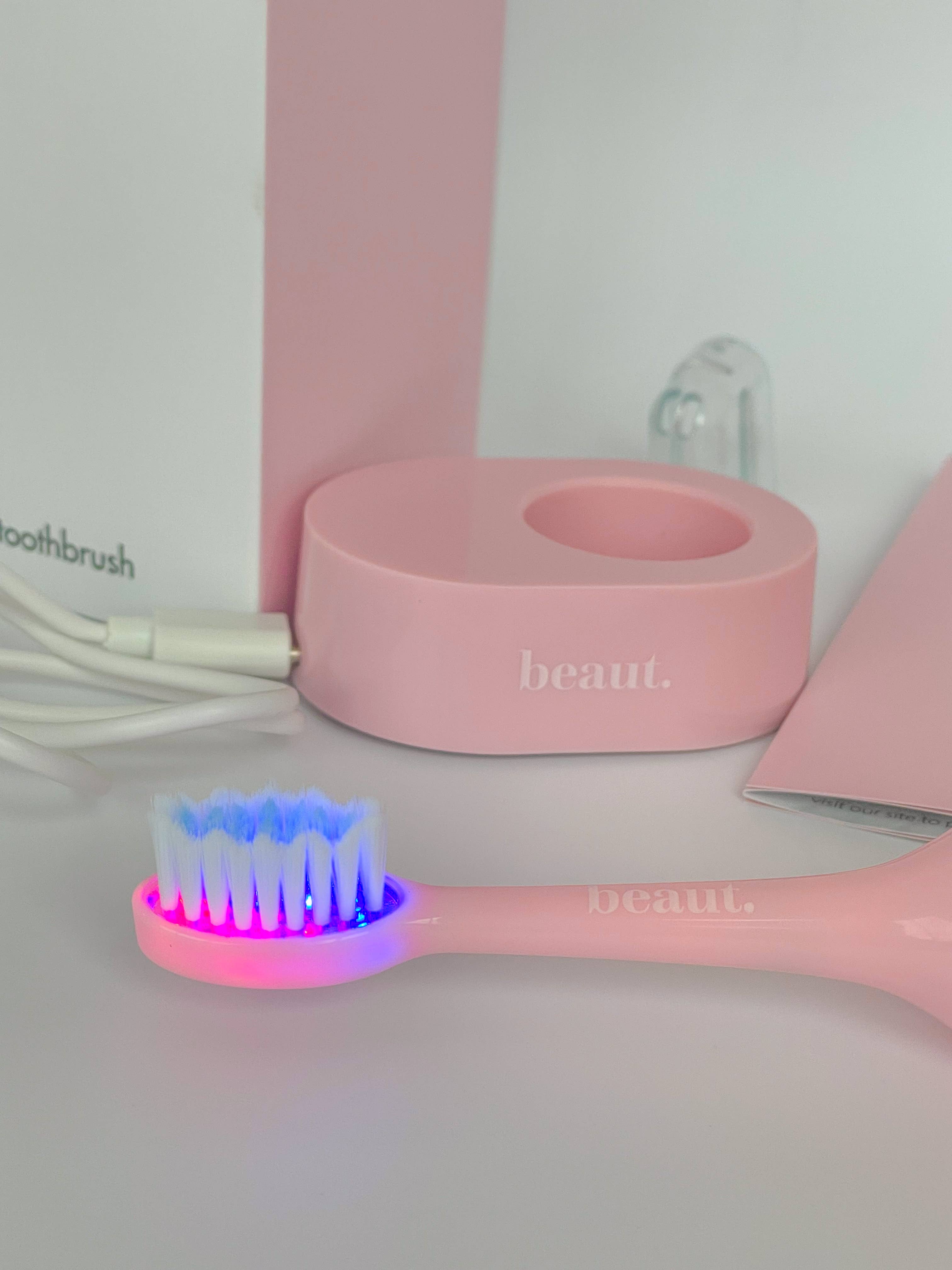 Pink Smile Kleen Sonic Vibration Toothbrush with blue and red light feature, accompanied by a matching holder.